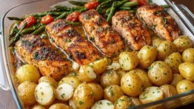 Sheet Pan Salmon and Asparagus with Potatoes – roasted salmon fillets, baby potatoes, and fresh asparagus with cherry tomatoes, garnished with herbs in a glass dish.