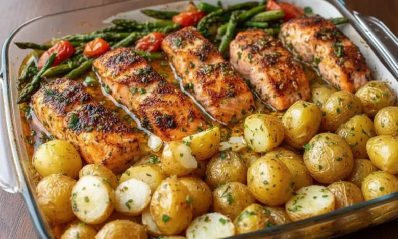 Sheet Pan Salmon and Asparagus with Potatoes – roasted salmon fillets, baby potatoes, and fresh asparagus with cherry tomatoes, garnished with herbs in a glass dish.