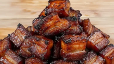 Close-up of smoked pork belly cubes with crispy edges and juicy tender interior, piled on a wooden surface.