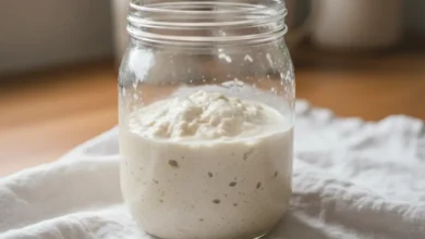 Sourdough starter in a glass jar, bubbling and fermenting on a clean kitchen cloth.