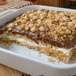 Peanut Butter Crunch Lasagna with layers of peanut butter, creamy filling, and crunchy toppings in a white dish.