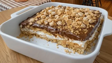 Peanut Butter Crunch Lasagna with layers of peanut butter, creamy filling, and crunchy toppings in a white dish.