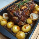 Honey roasted pork with caramelized onions and baby potatoes in a roasting pan
