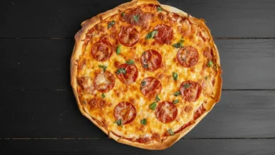 A freshly baked sourdough pizza with pepperoni slices, melted cheese, and basil leaves on a rustic wooden table, showcasing a golden and crispy crust.