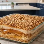 Peanut Butter Crunch Lasagna with creamy layers, peanut butter drizzle, and crunchy topping in a glass baking dish