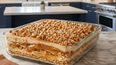 Peanut Butter Crunch Lasagna with creamy layers, peanut butter drizzle, and crunchy topping in a glass baking dish