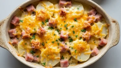 Cheesy ham and potato casserole baked until golden with melted cheese, sliced potatoes, and chunks of ham in a ceramic baking dish