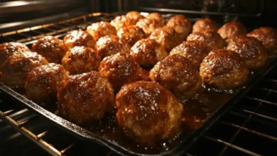 Oven baked BBQ meatballs caramelizing in the oven with glossy barbecue sauce on a baking tray