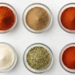 Small glass bowls filled with chili powder, cumin, paprika, garlic powder, oregano, and cayenne for homemade chili seasoning recipe