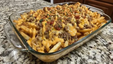 Cheeseburger French Fry Casserole in glass baking dish with crispy fries, seasoned ground beef, melted cheese, and fresh herbs on top