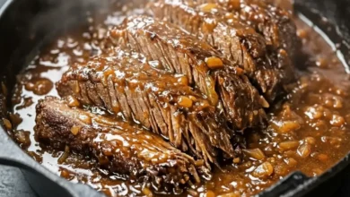 Tender slow cooker beef tips in rich brown gravy with onions, served hot in a skillet.