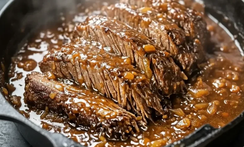 Tender slow cooker beef tips in rich brown gravy with onions, served hot in a skillet.