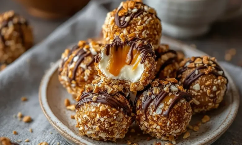 Salted caramel pretzel cheesecake balls coated in crushed pretzels and chopped nuts, drizzled with chocolate, with one ball cut open showing creamy filling and caramel center.