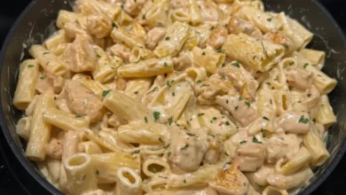 Creamy parmesan garlic chicken pasta with rigatoni and chicken pieces in a skillet, topped with parsley