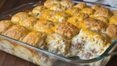 Close-up of biscuits and gravy casserole in a glass baking dish with golden biscuits, creamy sausage gravy, and melted cheddar cheese.