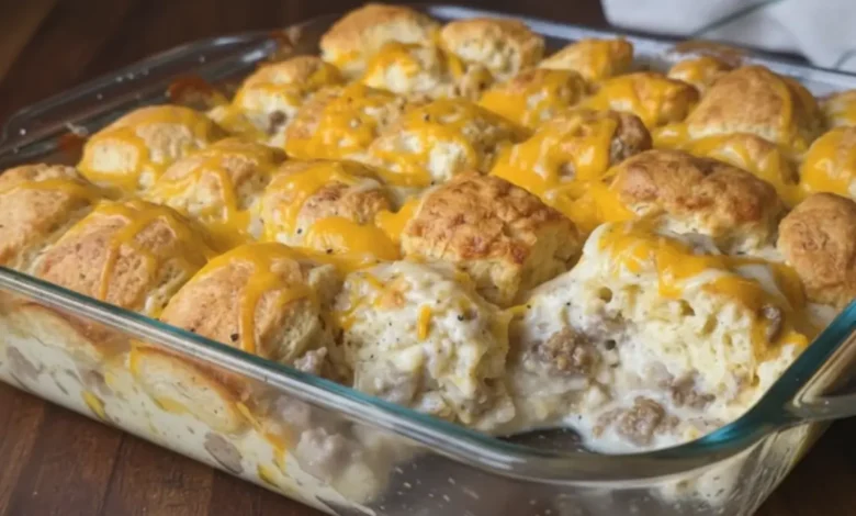 Close-up of biscuits and gravy casserole in a glass baking dish with golden biscuits, creamy sausage gravy, and melted cheddar cheese.